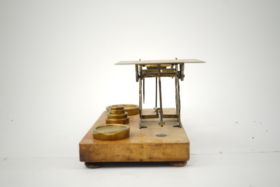 A Sampson Mordan & Co. set of brass postal scales on an oak base with weights, 27cm wide, with engraved prices for Inland Letter Post, etc.